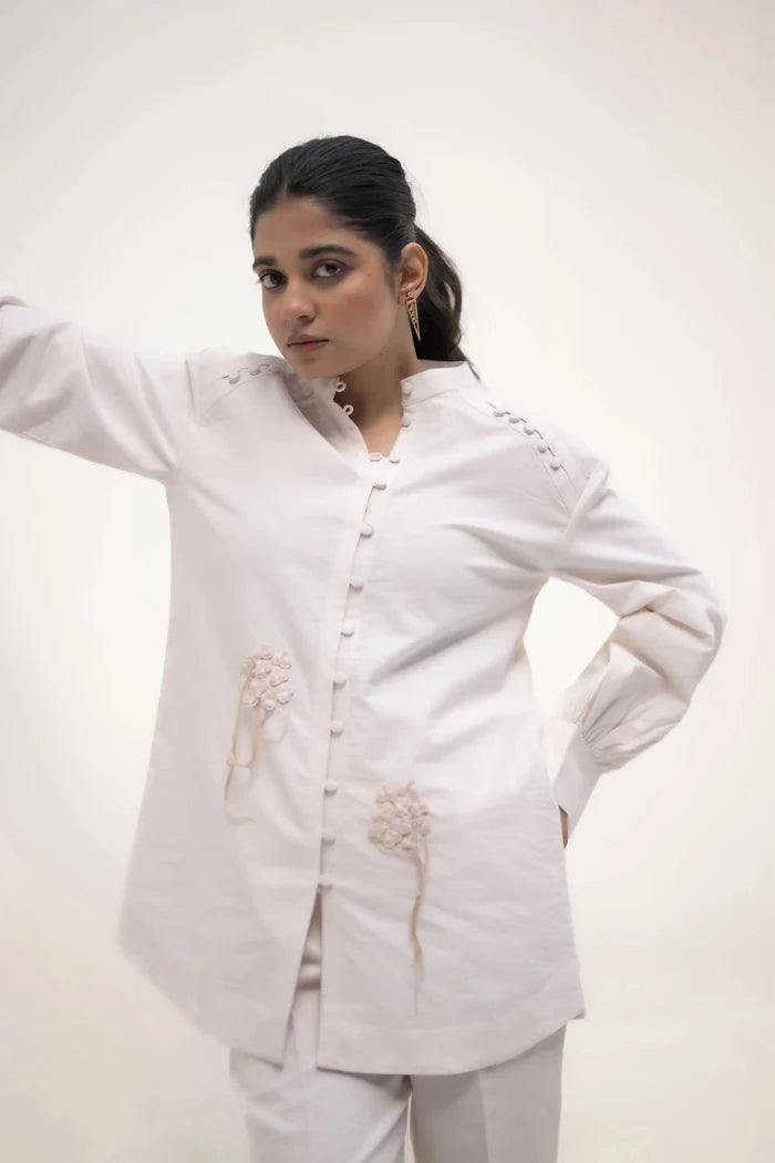 The model in white outfit, standing with one hand on her waist, looking slightly to the side with a calm expression.