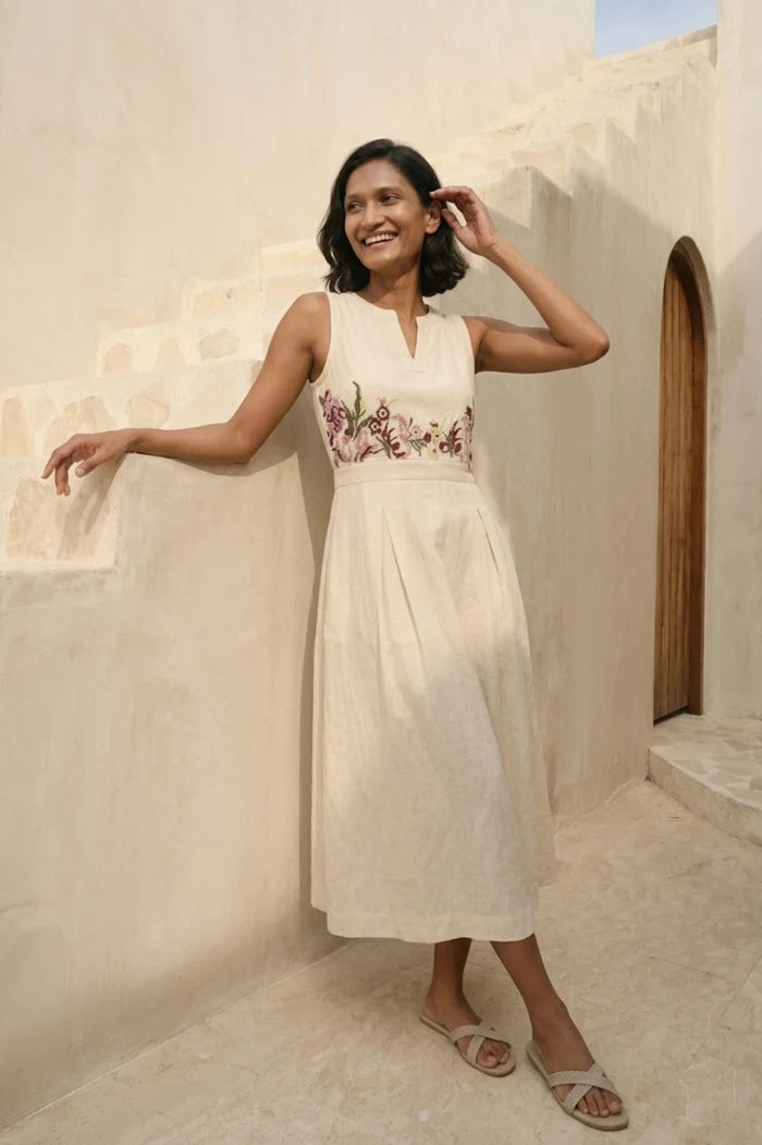 Model wearing Celia Linen Midi cream dress with V-notch neckline and pleated skirt – floral embroidered dress for brunch and resort wear