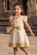 The Nesavu Silk Frock Girls Short Frocks for Party in Beige Silk with Gold Bow Embellishment and Checked Pleated Design Nesavu 16 (1Y) / Cream SF1010B-16 Nesavu Girls Short Frocks Party Beige Silk Gold Checked Pleats Bow Embellishment
