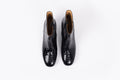Izzy Boot by Otto + Ivy - an aerial profile of a black boot for tall women with large feet, featuring glossy black croc leather and a low chunky heel.