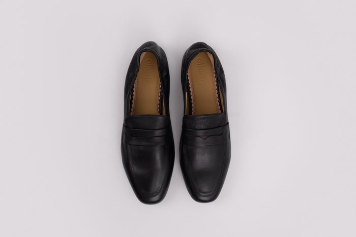 Pair of large size 9 black loafers on a light gray background