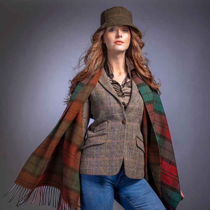 Woman wearing a plaid coat, hat, and blue jeans against a gray background